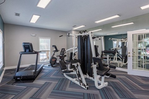 a gym with cardio machines and weights at the estates apartments