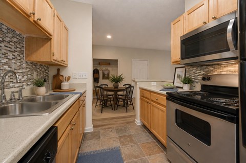 A kitchen with wooden cabinets and a black dishwasher.