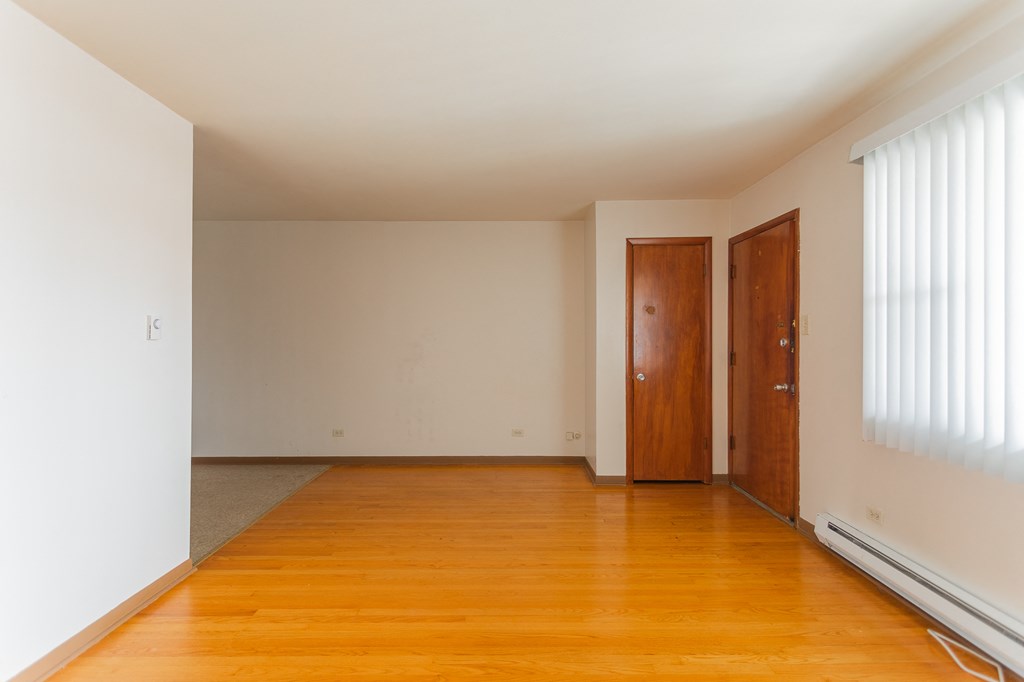 an empty living room with wood floors and white walls