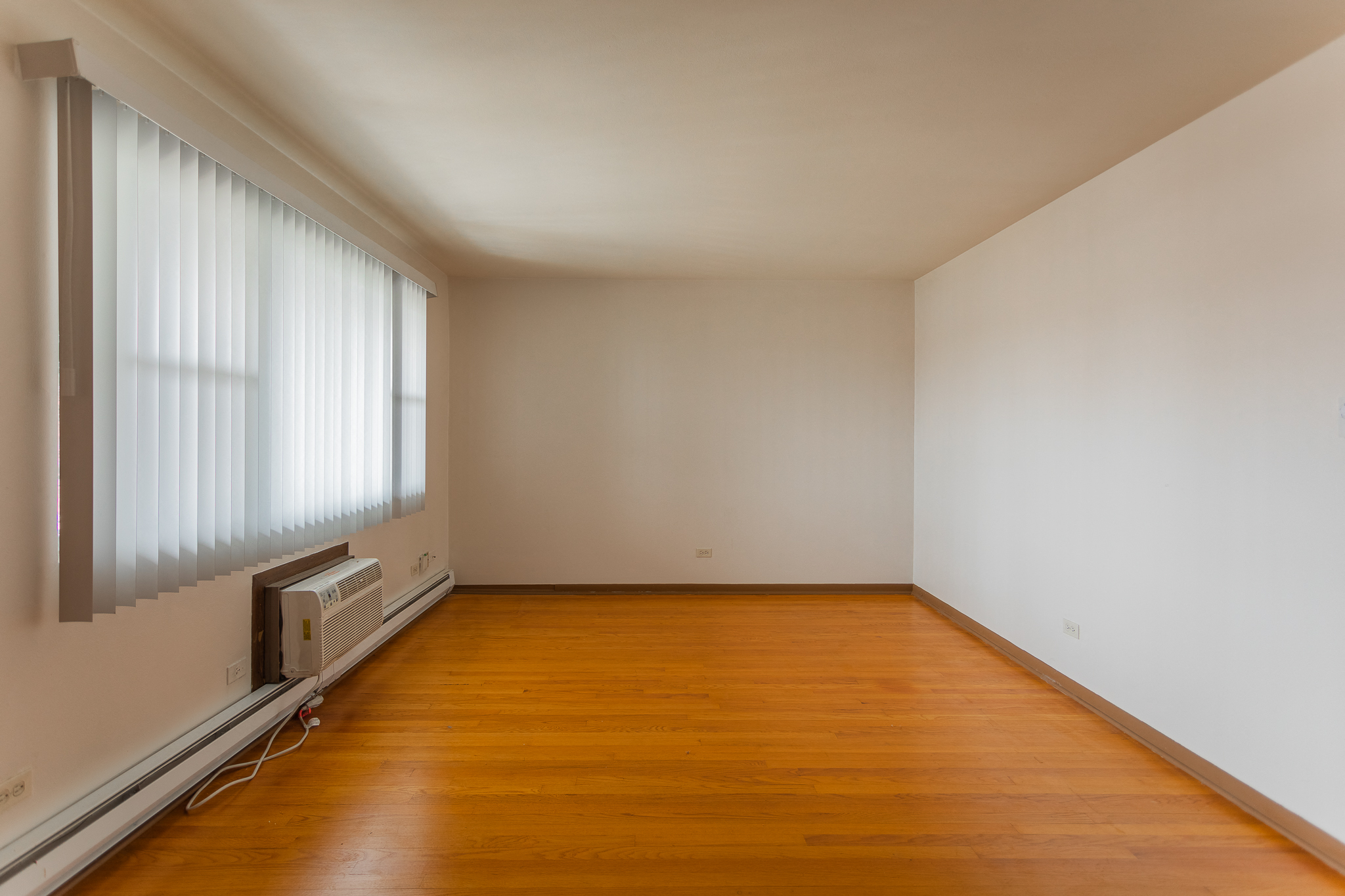 an empty living room with wooden floors and a window