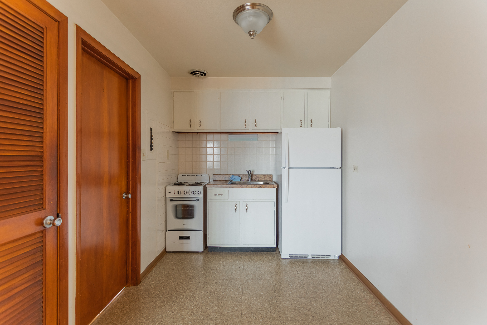 an empty kitchen with white appliances and white cabinets