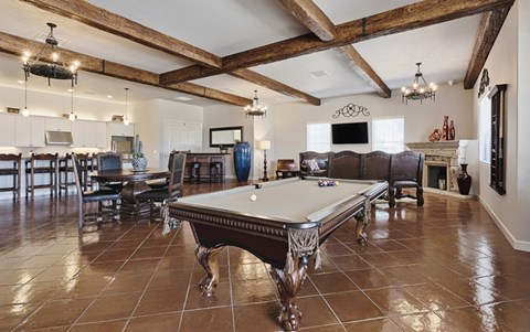 a pool table in a living room with a dining room and a kitchen