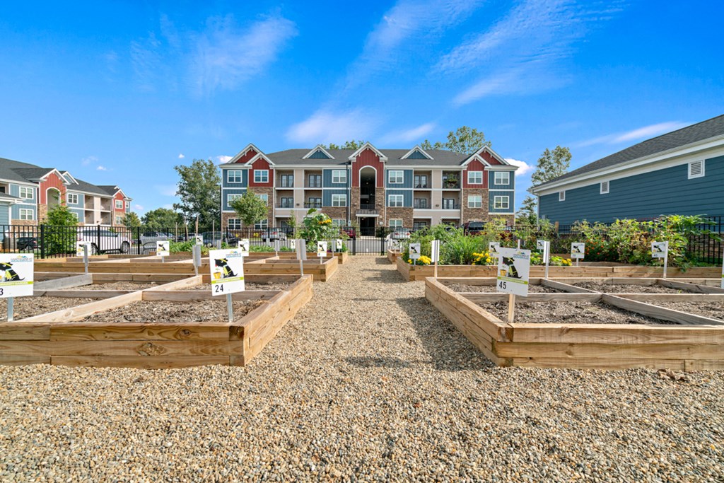 a community garden with raised beds in front of an apartment building