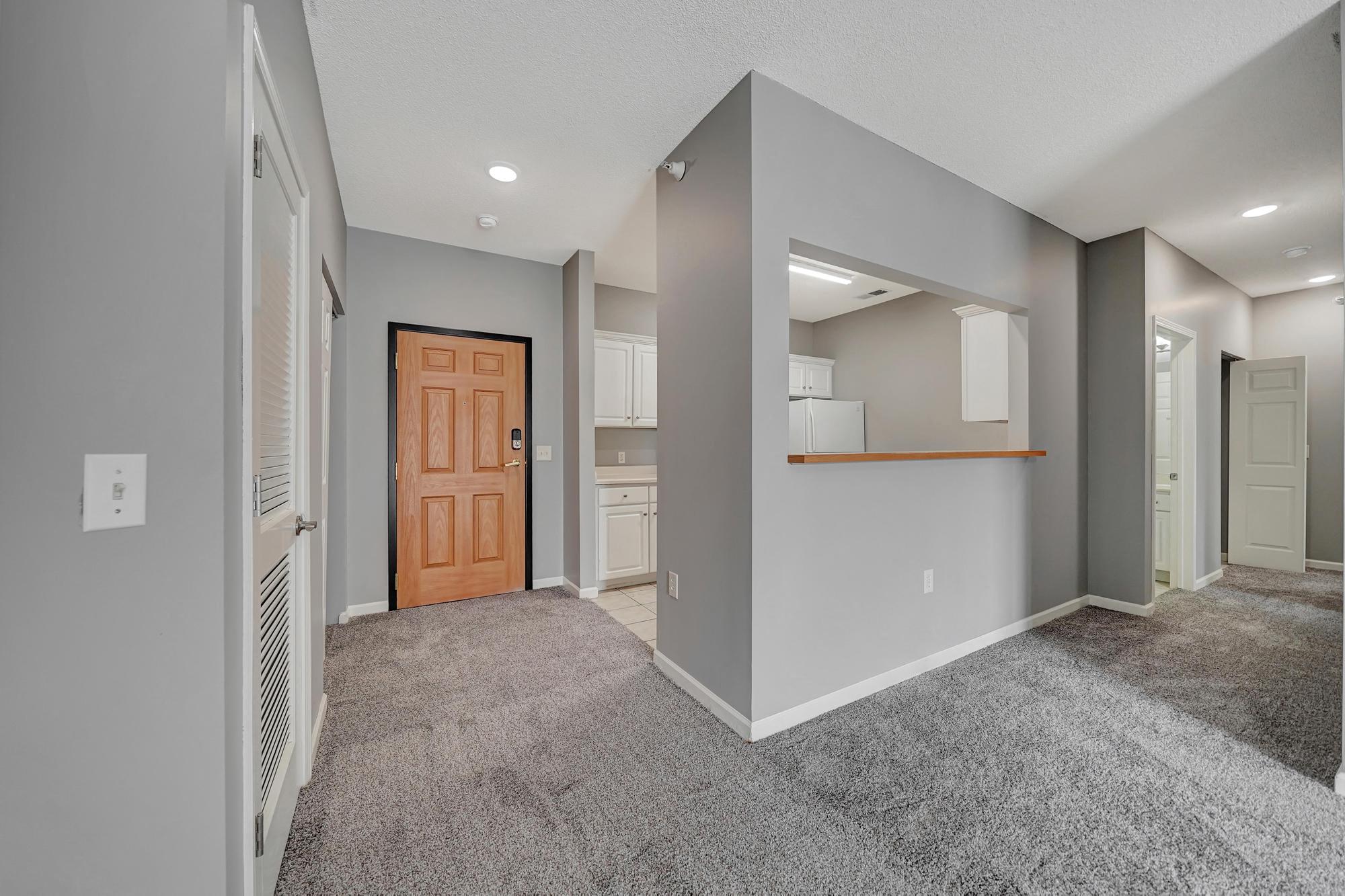 an empty living room with a door to a kitchen