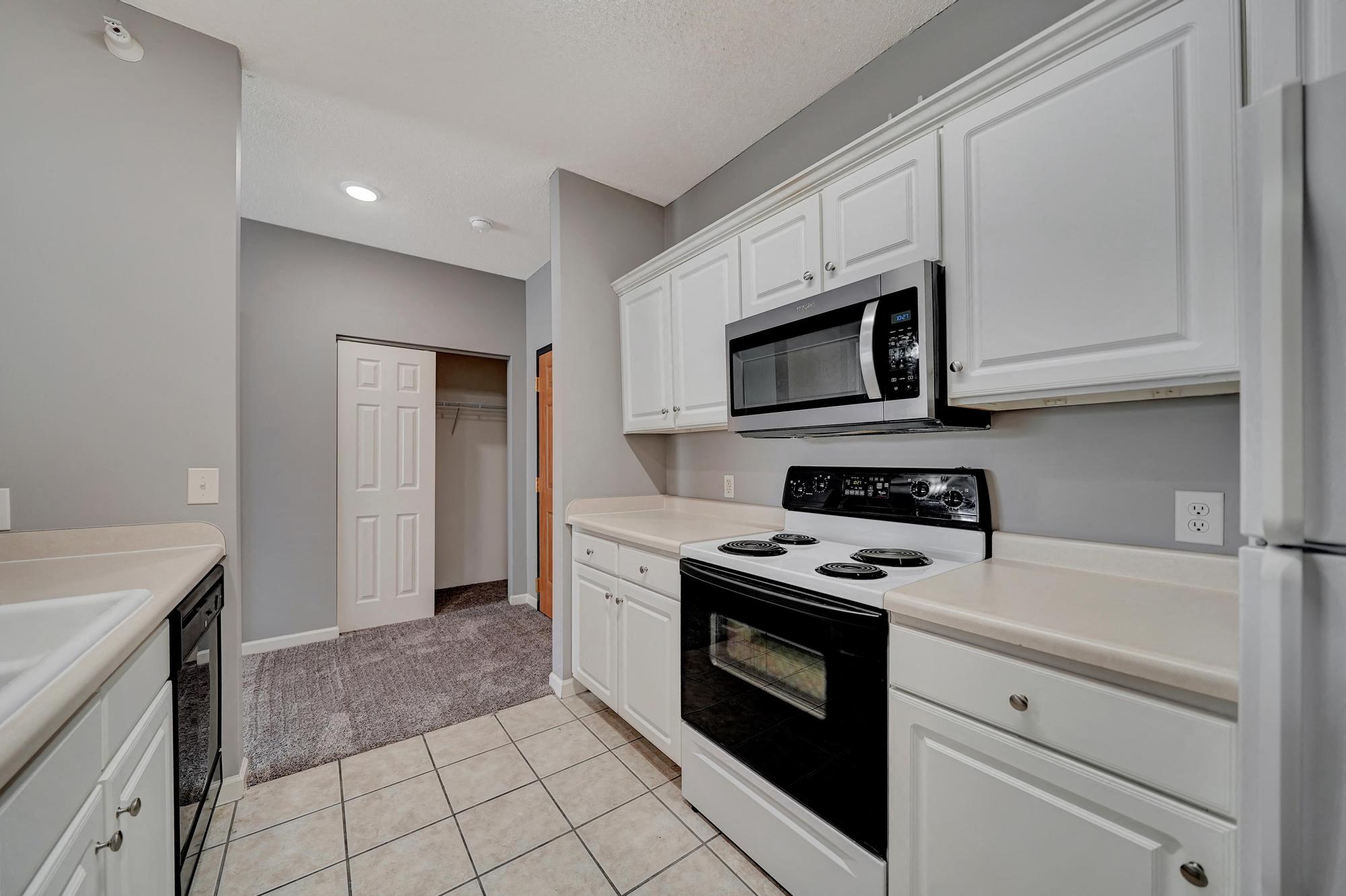 a kitchen with white cabinets and black appliances