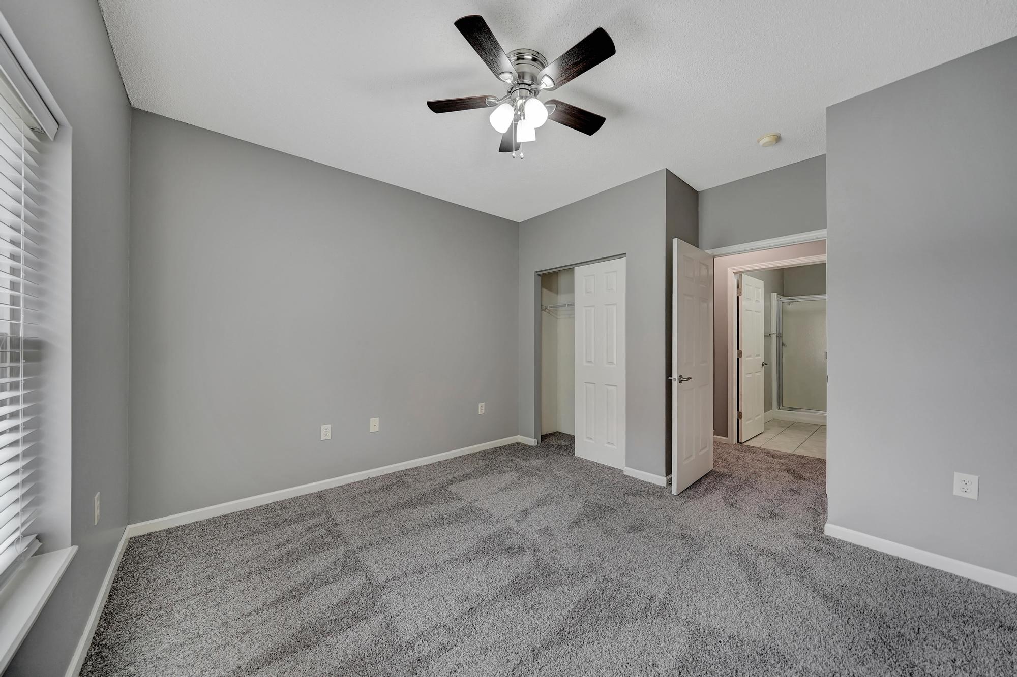 an empty living room with a ceiling fan