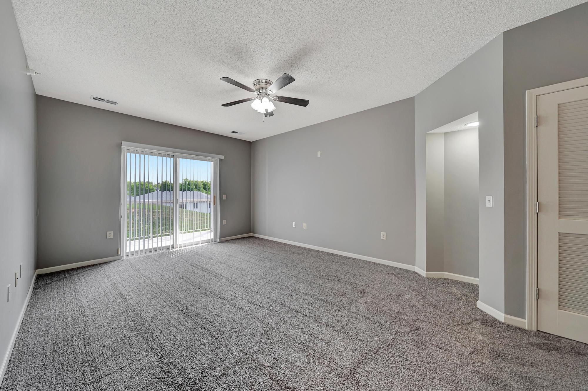 an empty living room with a ceiling fan and a window