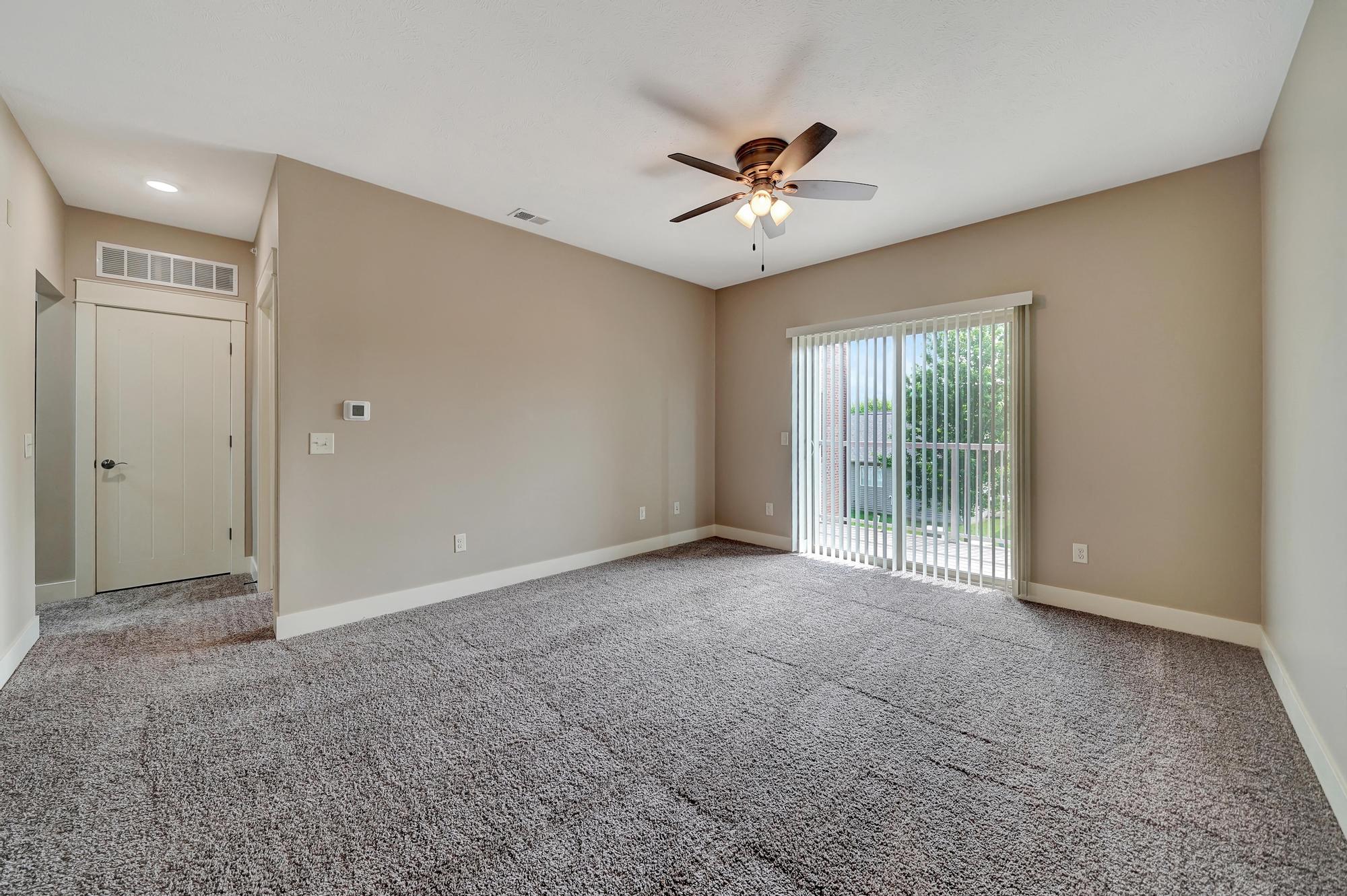 an empty living room with a ceiling fan and a window