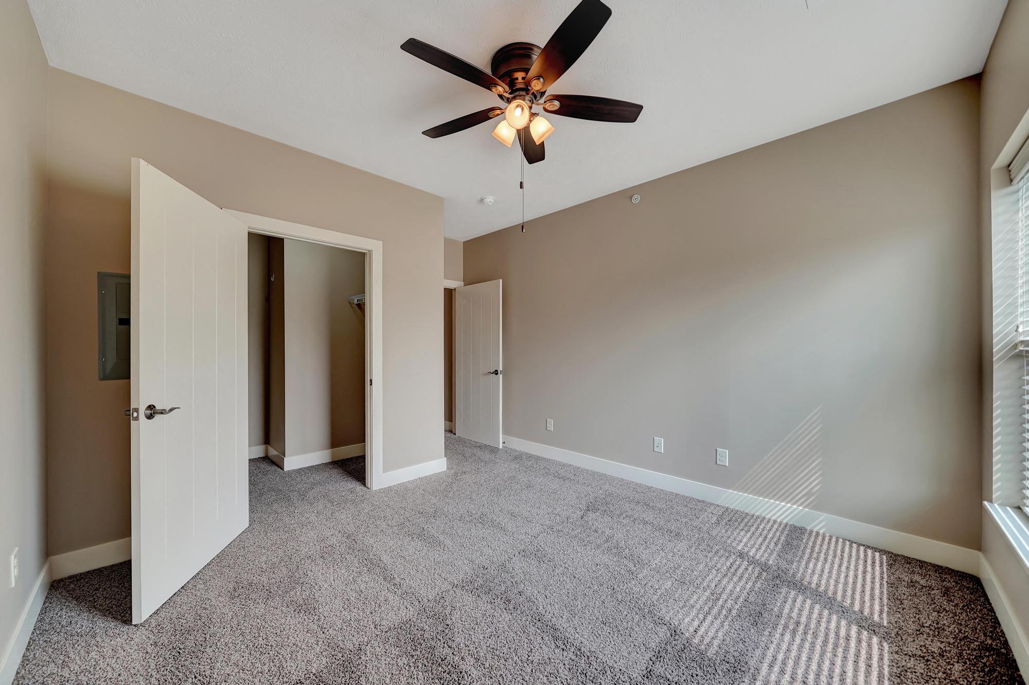 an empty living room with a ceiling fan