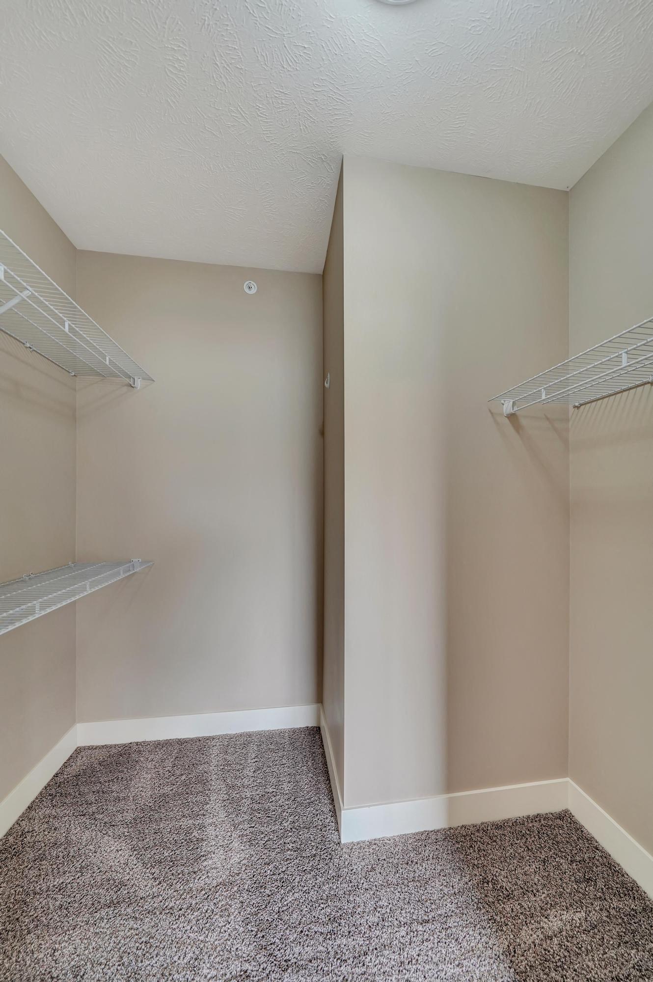 a spacious closet with shelves and a mirrored closet door in an empty room