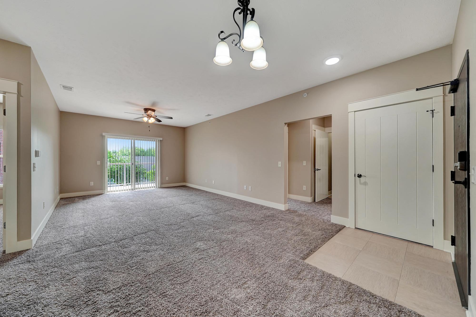 an empty living room with a ceiling fan and a door to a closet