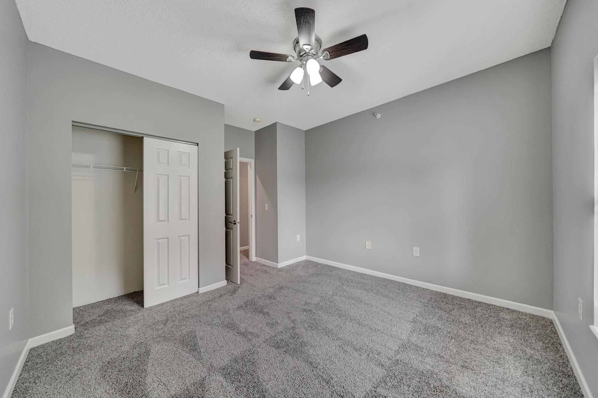 an empty living room with a ceiling fan and a closet