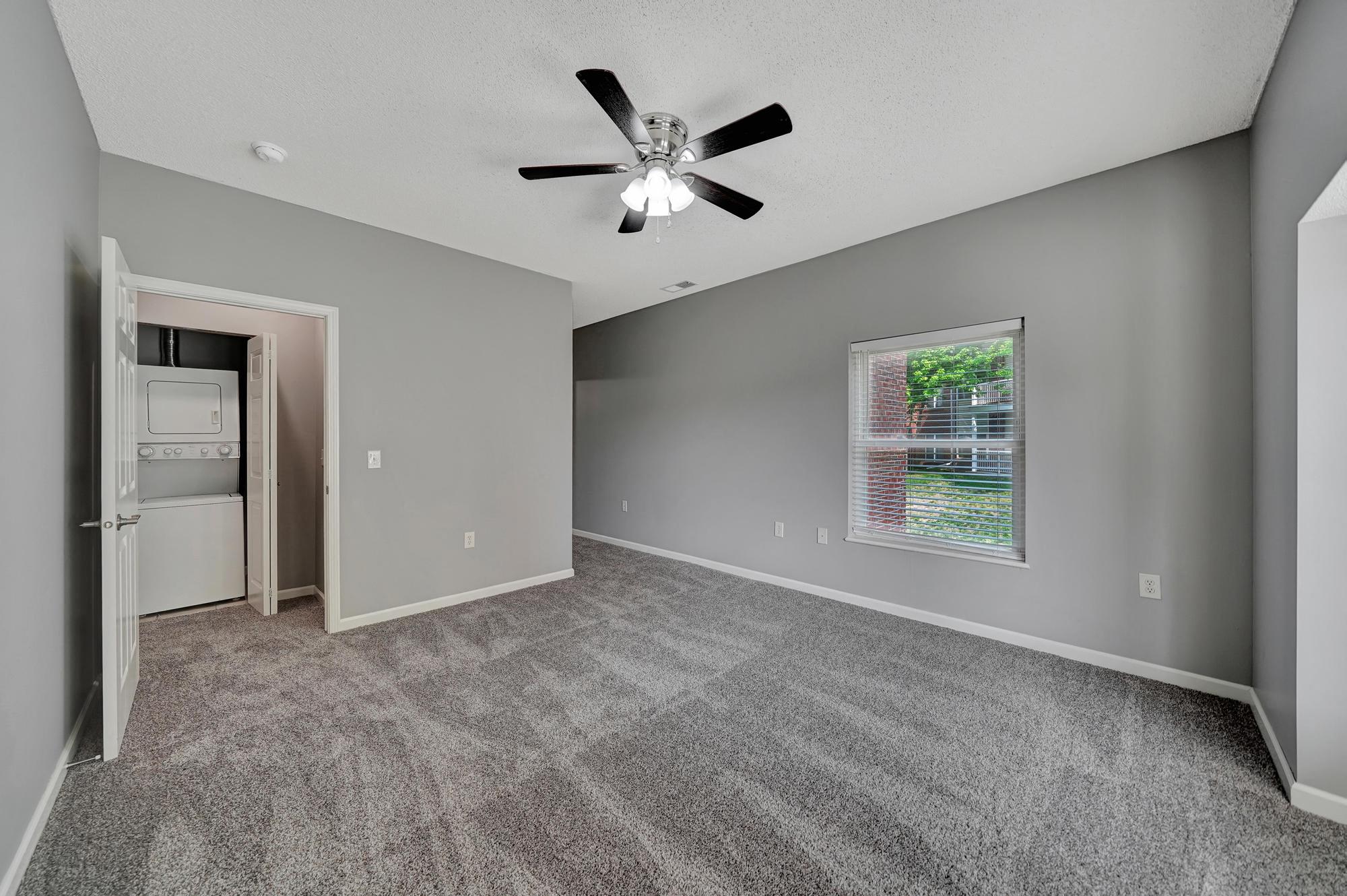 an empty living room with a ceiling fan and a window