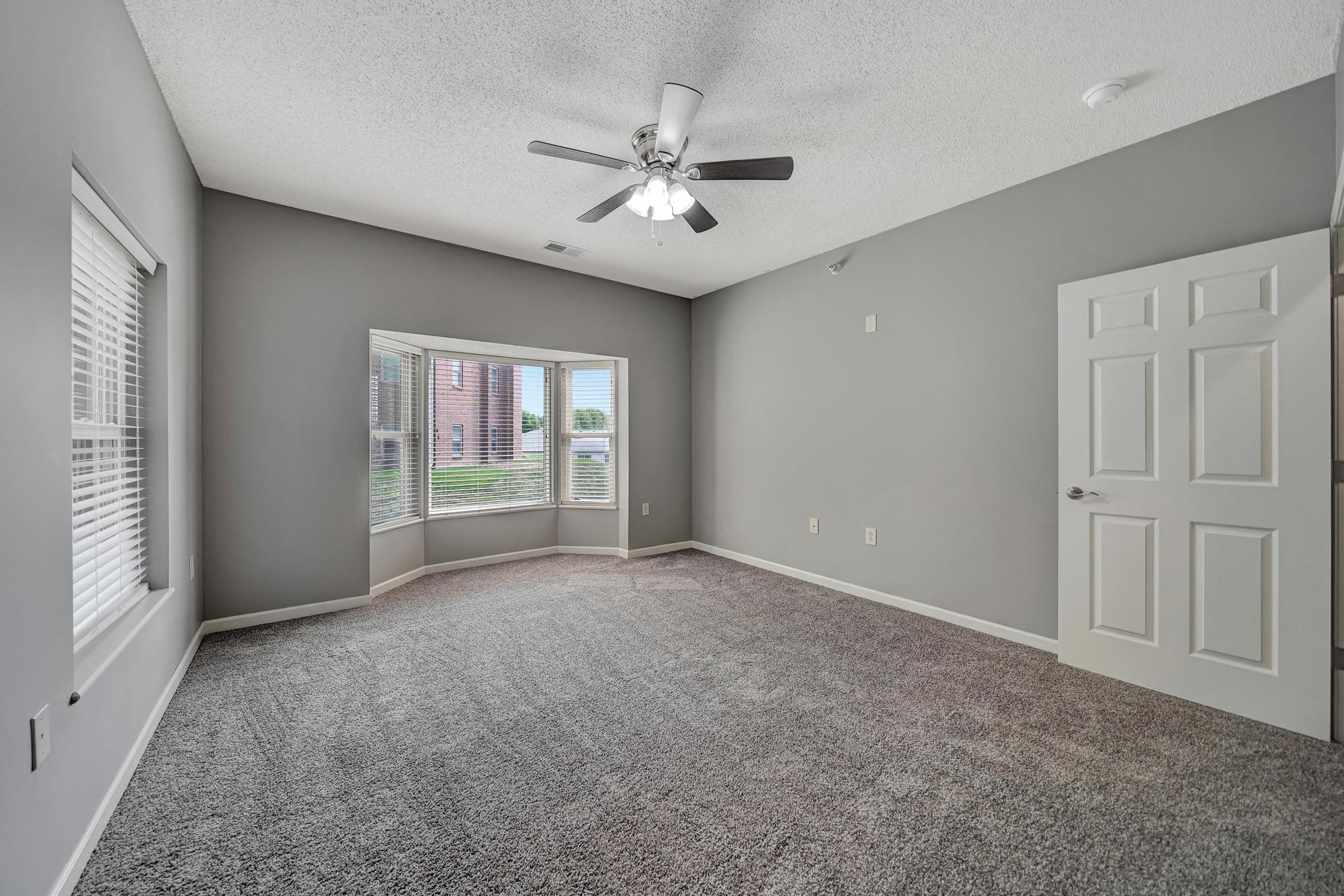 an empty living room with a ceiling fan and a window