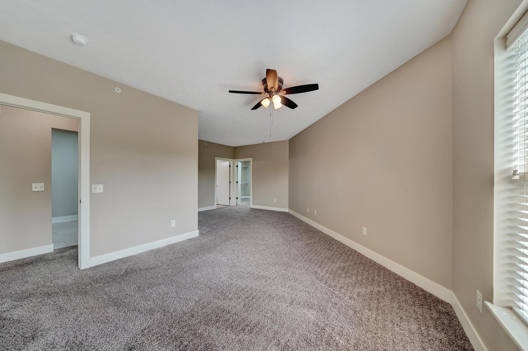 an empty living room with a ceiling fan and window