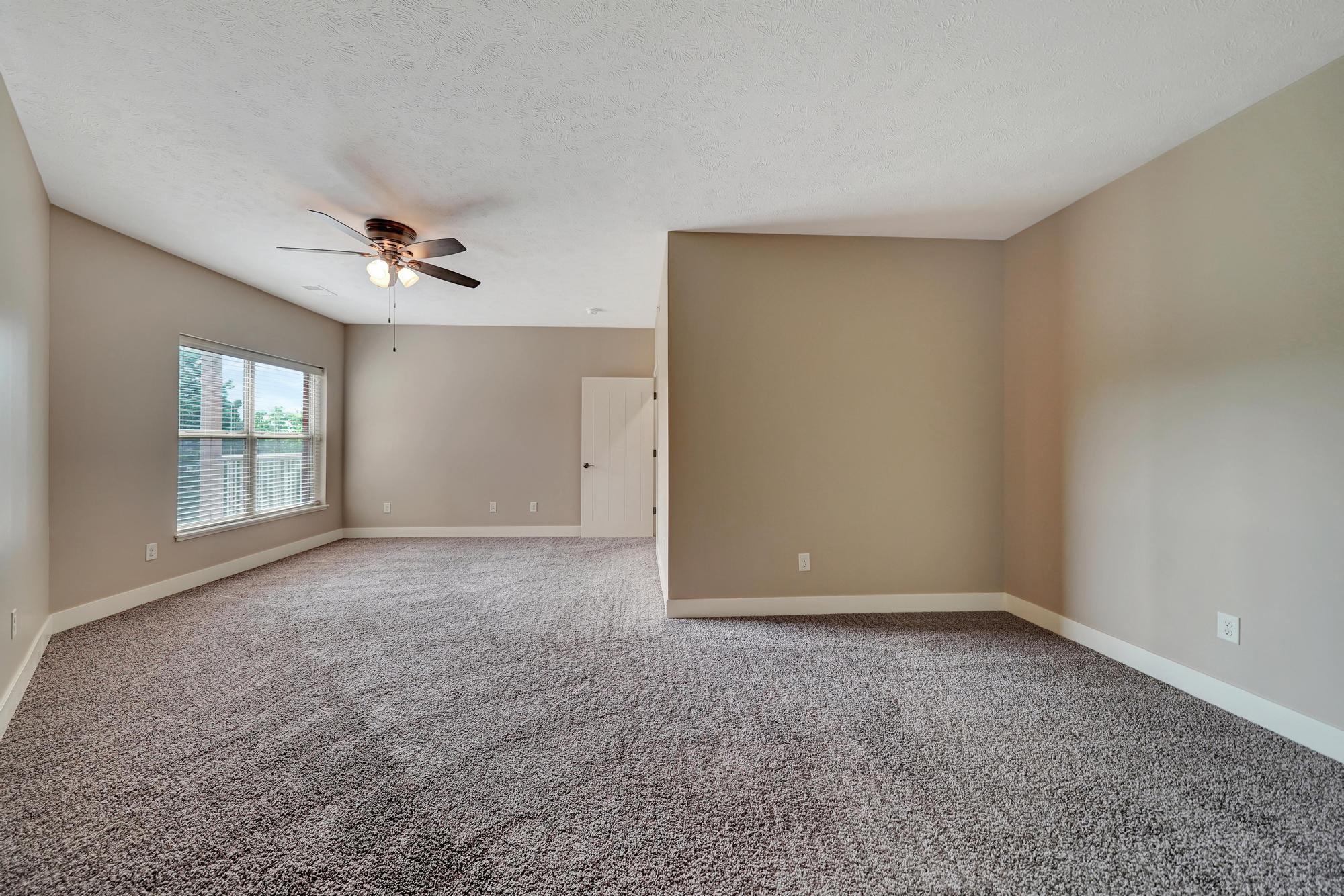 an empty living room with a ceiling fan and a window