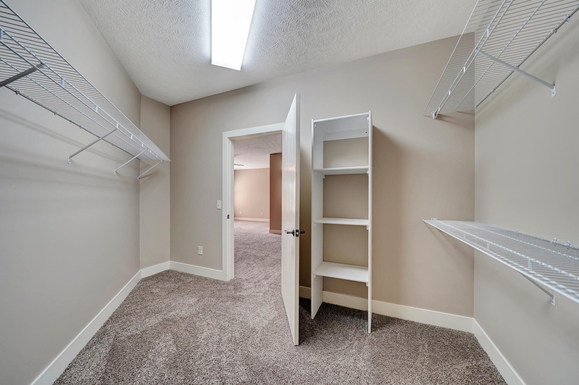 a walk in closet with shelves and a mirrored closet door