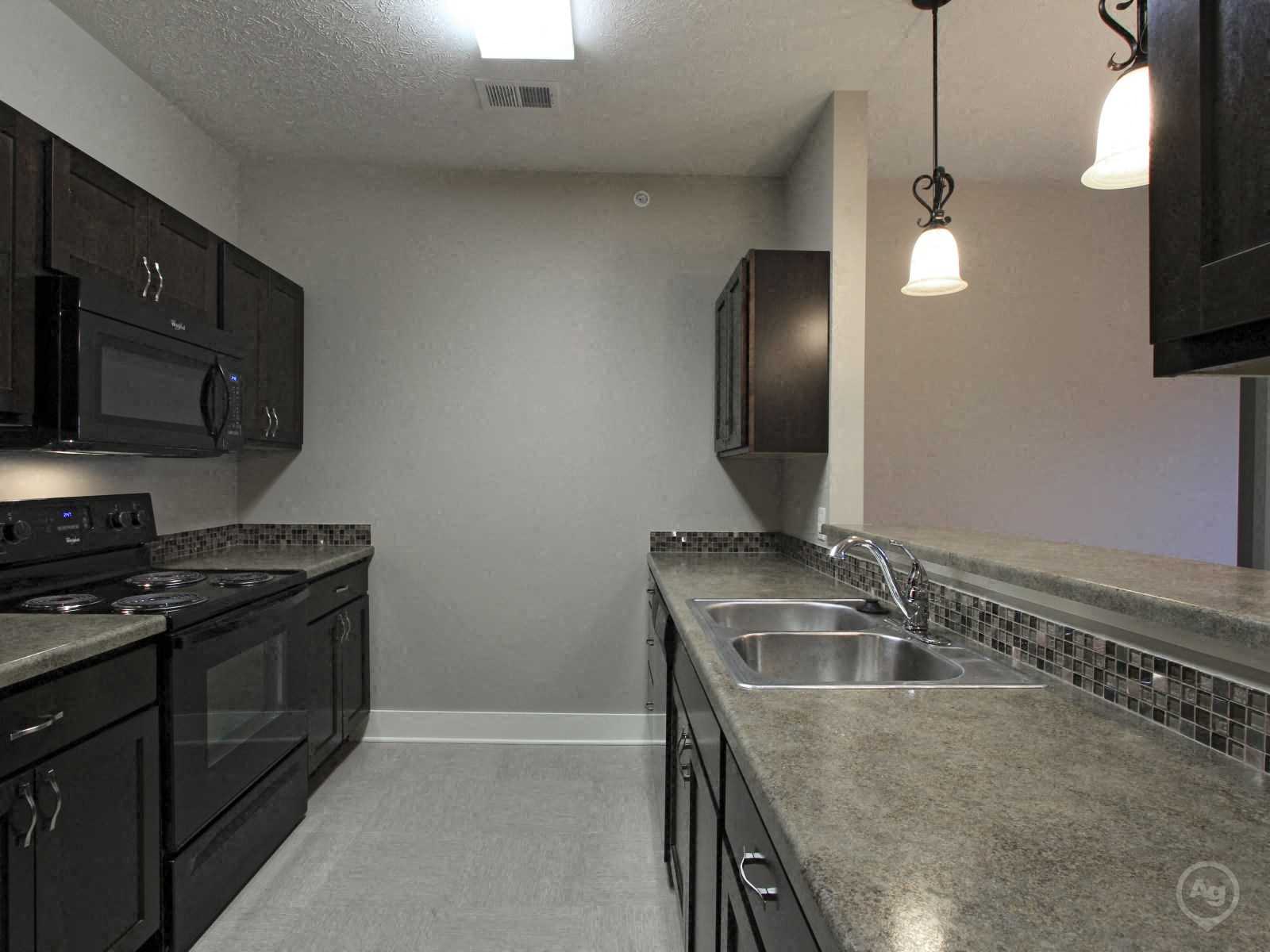 A kitchen with black cabinets and a granite countertop.