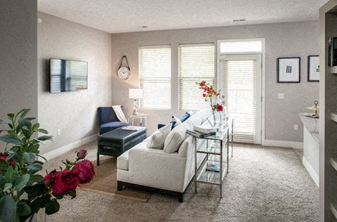A living room with a sofa, a coffee table, and a vase of flowers.