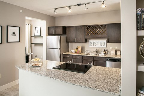 A kitchen with a granite counter top and a bistro sign above the sink.