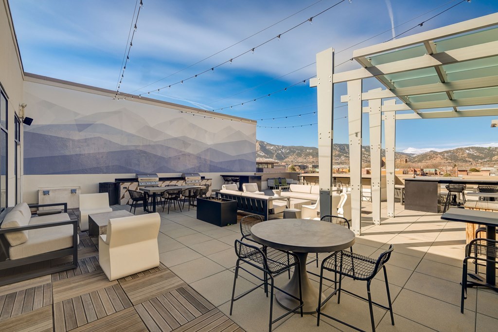 A patio with a table and chairs overlooking a mountain range.