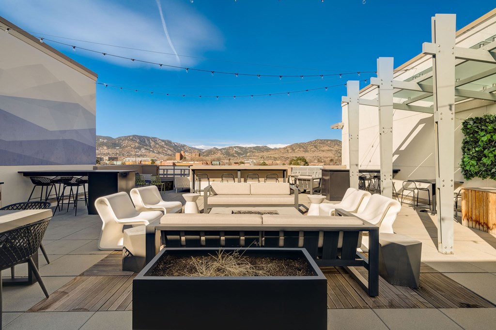 A patio with a white couch and chairs is set up on a wooden deck.