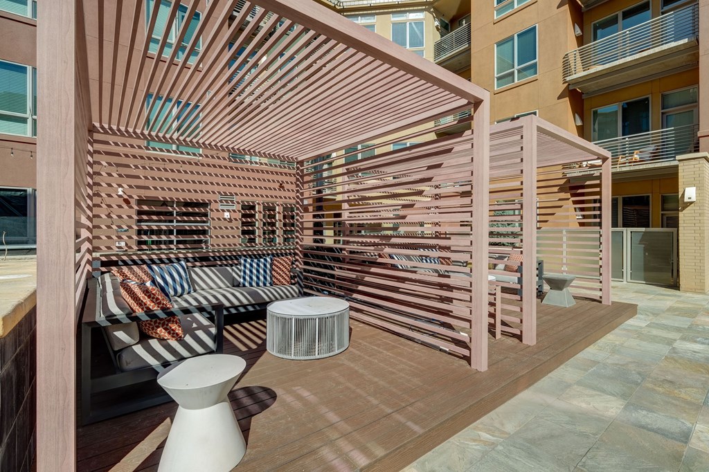 A patio with a wooden pergola and a striped couch.
