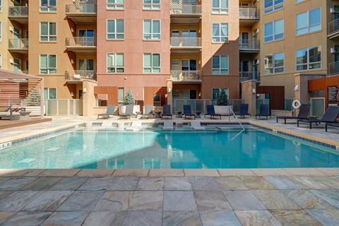 A swimming pool in front of a multi-story apartment building.