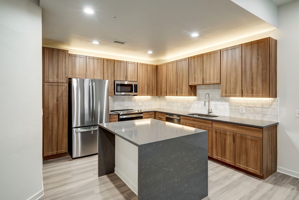 A modern kitchen with wooden cabinets and a marble island.