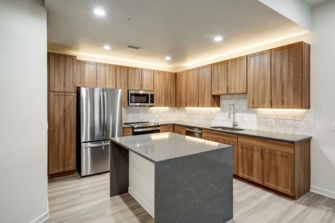 A modern kitchen with wooden cabinets and a marble island.