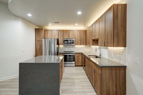 A modern kitchen with wooden cabinets and a marble island.