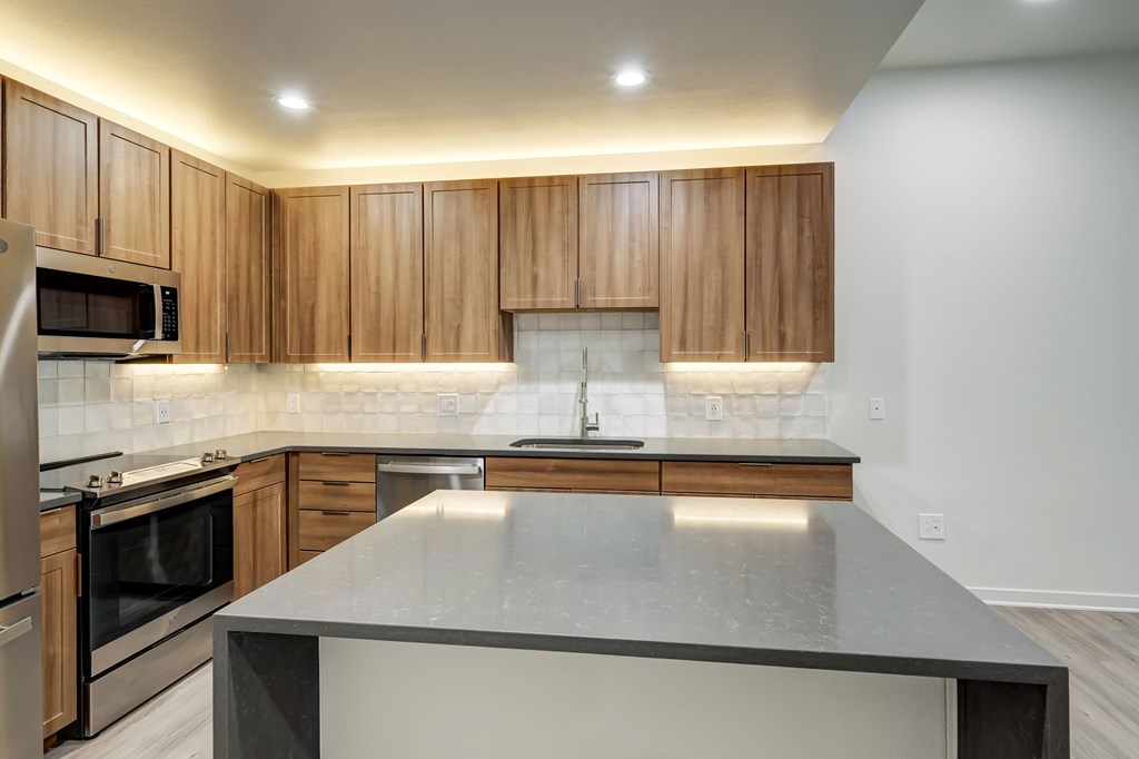 A modern kitchen with wooden cabinets and a granite countertop.