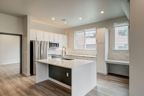 A modern kitchen with a white island and wooden floors.