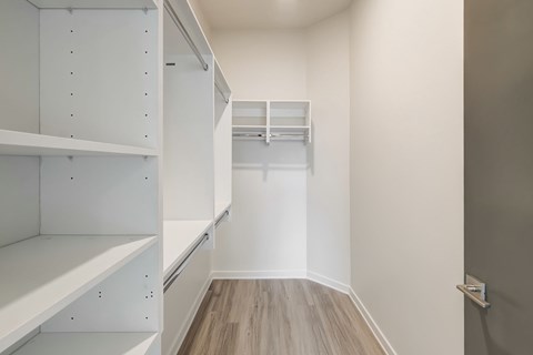 A white walk in closet with shelves and drawers.