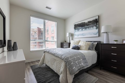 A bedroom with a large bed and a window overlooking a city street.