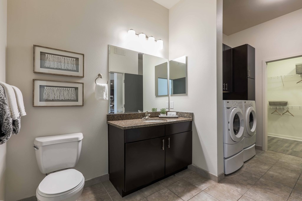 A bathroom with a toilet, sink, and mirror.