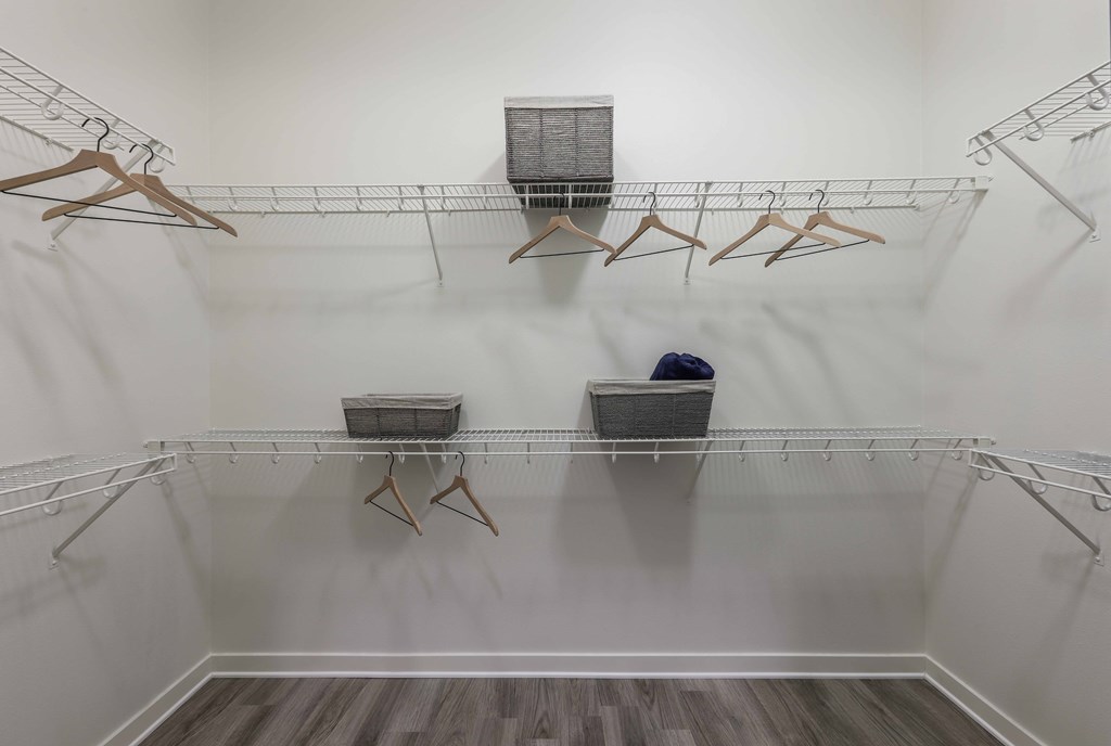 A walk-in closet with clothes hanging on racks and baskets on the floor.