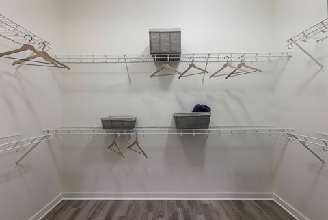 A walk-in closet with clothes hanging on racks and baskets on the floor.