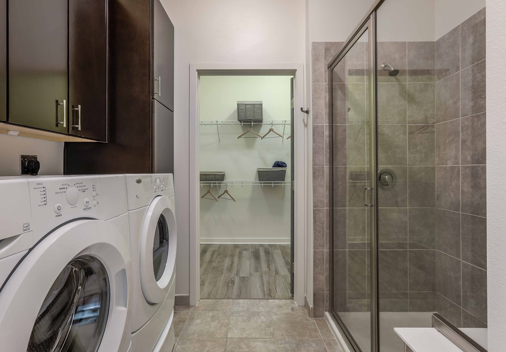 a washer and dryer in a laundry room with a shower and a bathroom