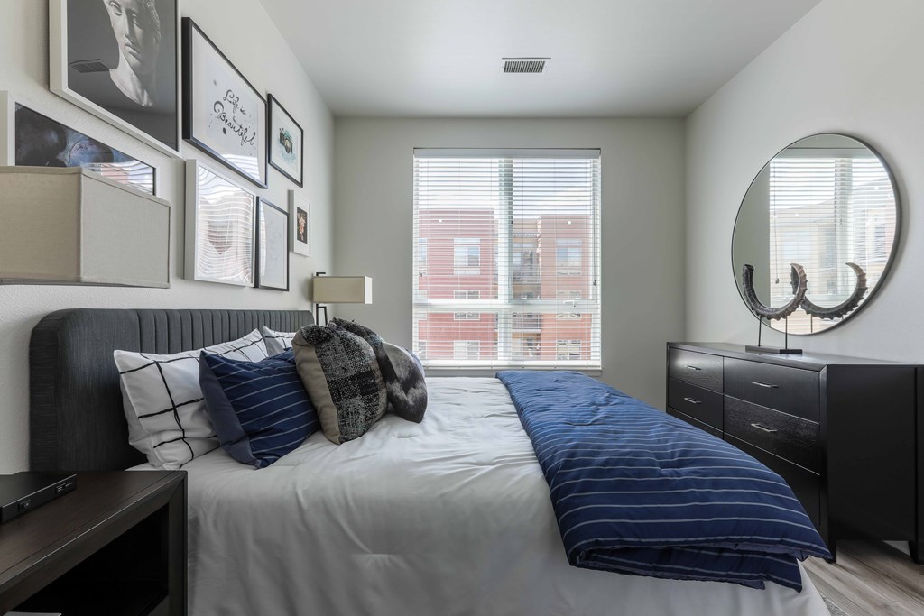 A bedroom with a bed, nightstand, and a mirror.