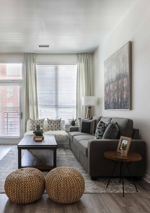 A living room with a grey couch, a coffee table, and two round wicker tables.