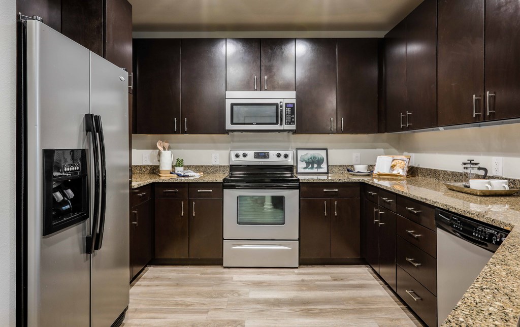 A kitchen with brown cabinets and a stainless steel refrigerator.