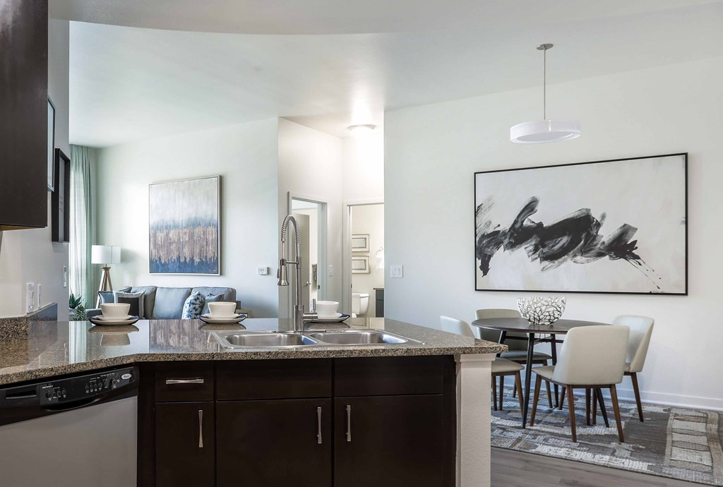 A modern kitchen with dark brown cabinets and a large abstract painting on the wall.