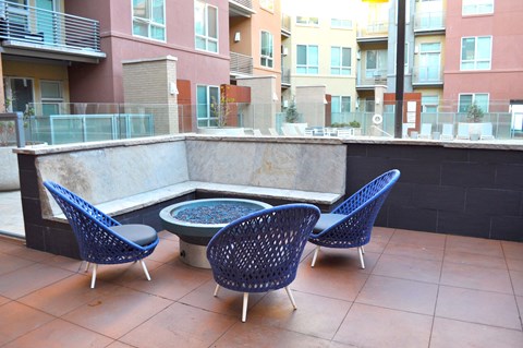 a patio with blue chairs and a fire pit