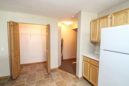 an empty kitchen with a white refrigerator and cabinets