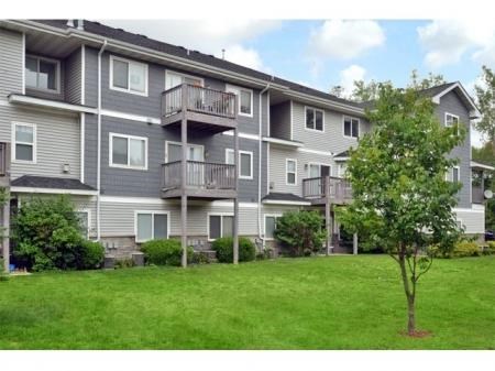 an apartment building with a tree in the yard
