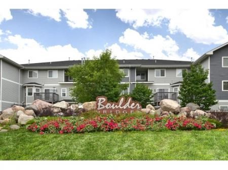 a sign in front of an apartment building with flowers