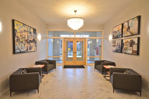 the lobby of a building with chairs and a chandelier