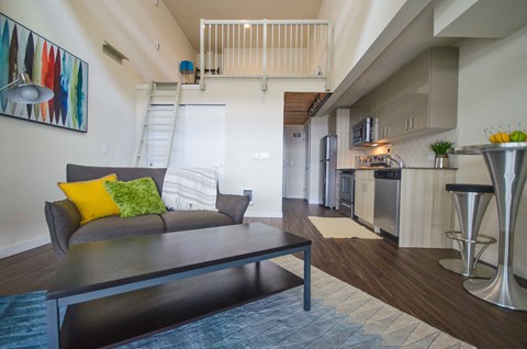 a living room with a couch and a table in front of a kitchen