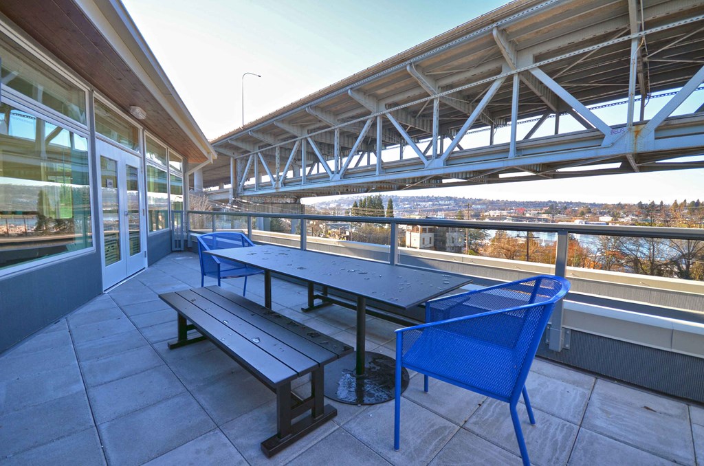 a patio with a picnic table and benches on a balcony